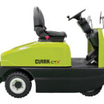 Side view of a Clark CTX70 electric tow tractor on a white background, featuring a seated operator position, steering controls, and a compact design for towing carts and transporting materials in industrial facilities.