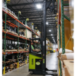 Clark NPX 17 order picker operating in a warehouse aisle, lifting an operator to access inventory stored on tall industrial shelving racks.